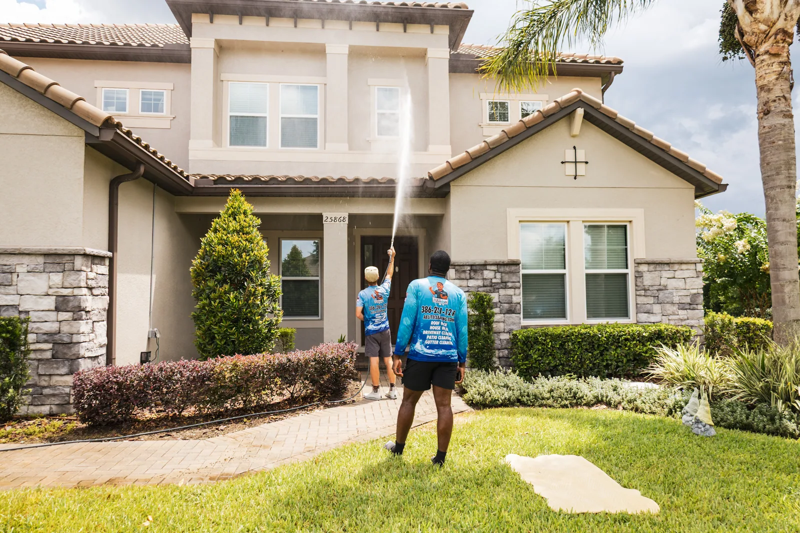 Two All Elite technicians softwashing a local Florida home